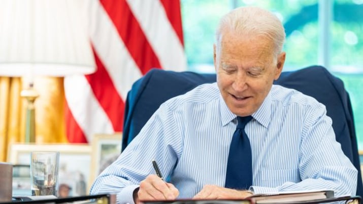 Presidente dos EUA, Joe Biden, sentado à mesa, escrevendo um memorando
