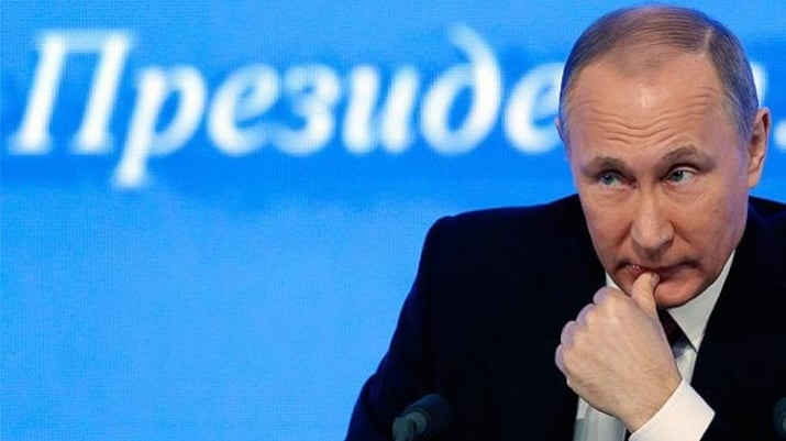 Presidente russo, Vladimir Putin, apoiado em uma mesa, com o dedão na boca