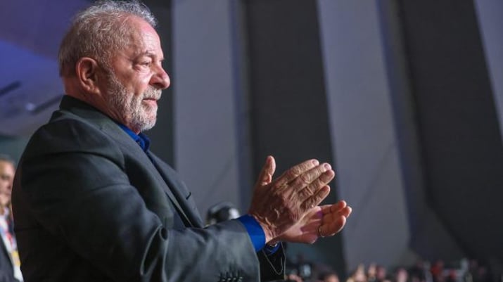 Luiz Inácio Lula da Silva de terno cinza escuro bate aplaudindo