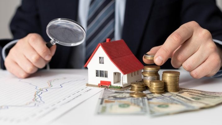 Miniatura de casa e moedas representando o investimento em fundos imobiliários