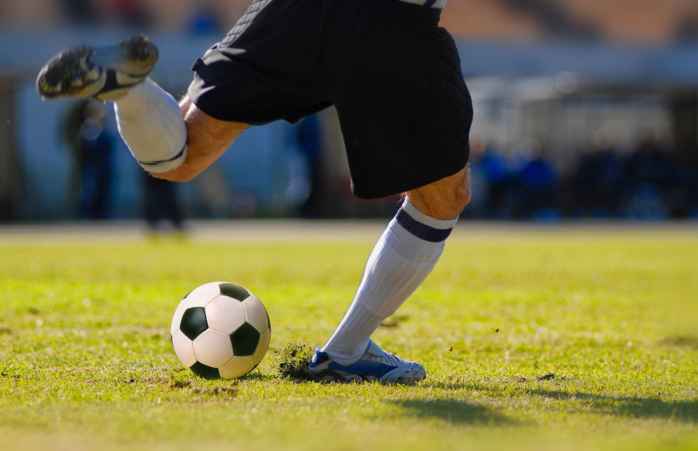 Jogador de futebol chuta bola