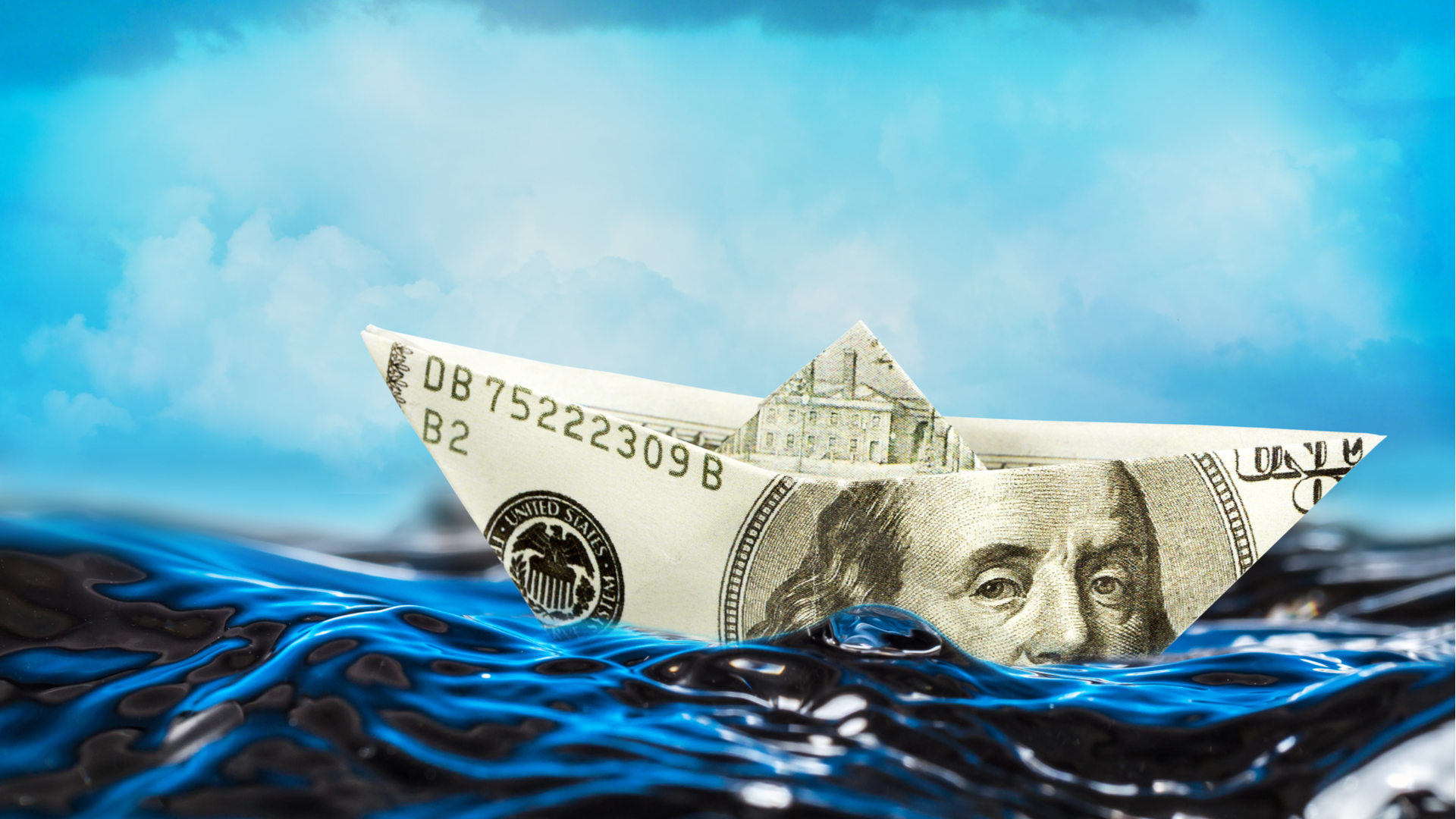 Barquinho feito com nota de dólar navegando no mar