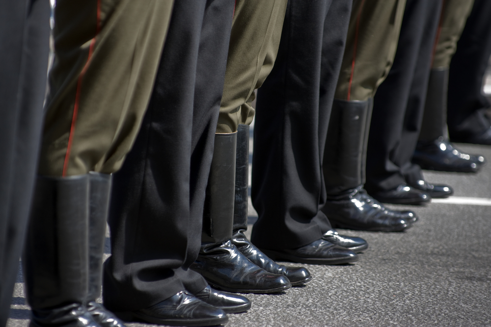 Pés de pessoas com sapato social e de militares com botas