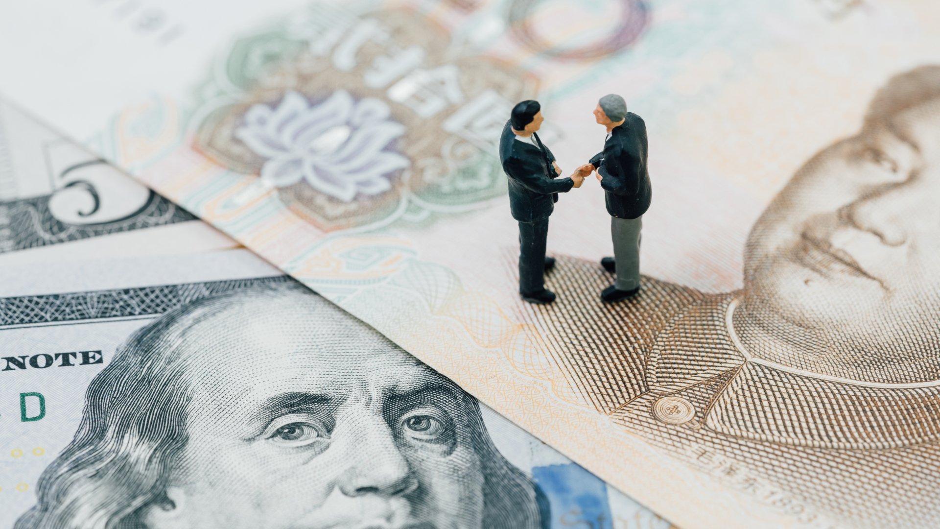 Montagem com dois bonecos dando as mãos, sinalizando um acordo entre EUA e China