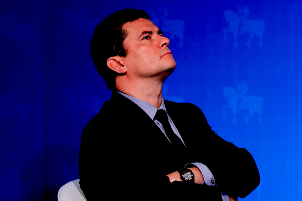 Sérgio Moro de braços cruzados em frente à um fundo azul