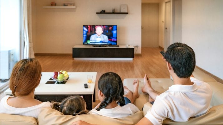 Família em frente à tv assistindo a programação.