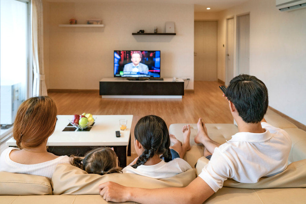 Família em frente à tv assistindo a programação.