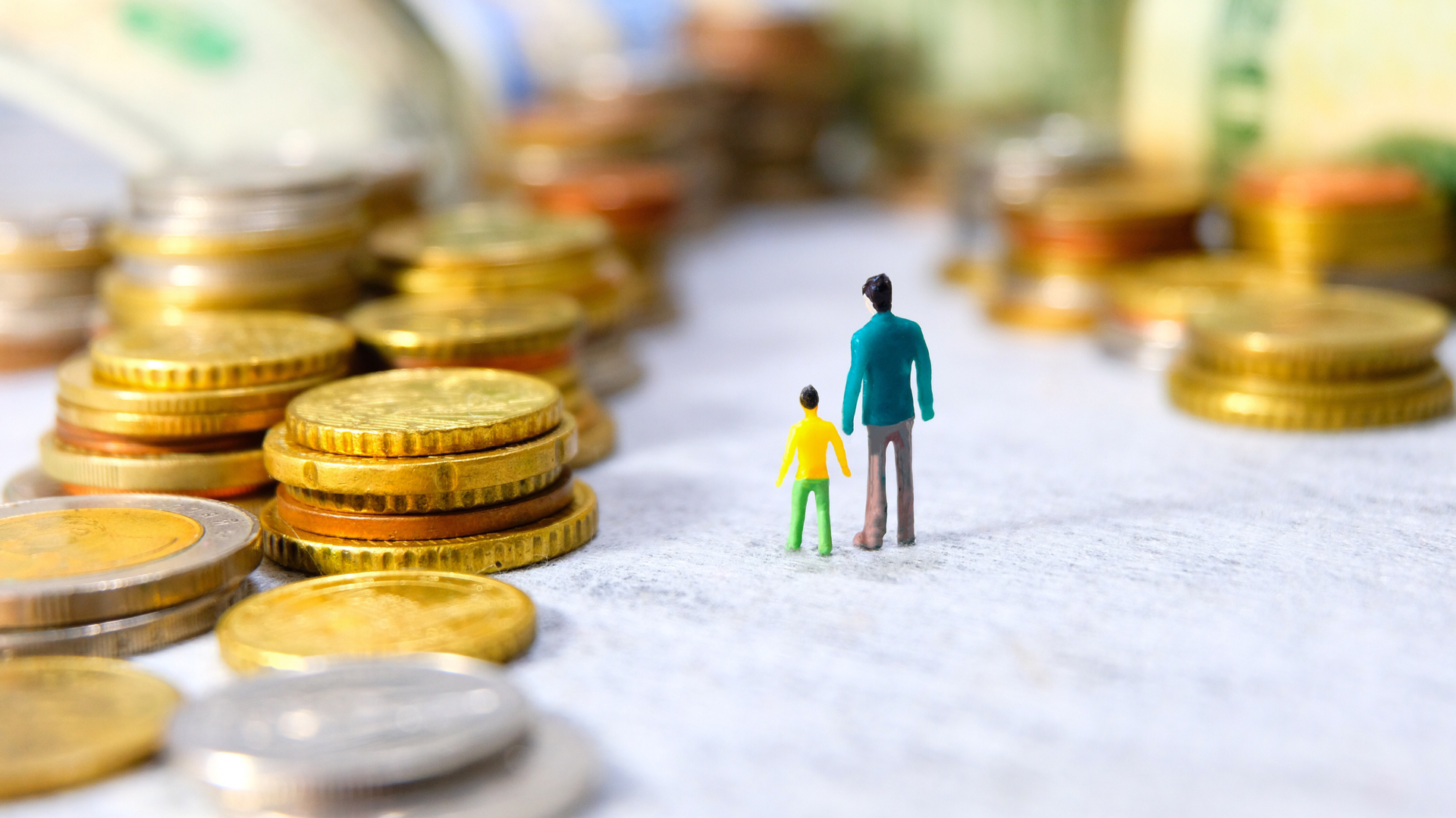 Miniatura de homem com filho frente à pilha de moedas