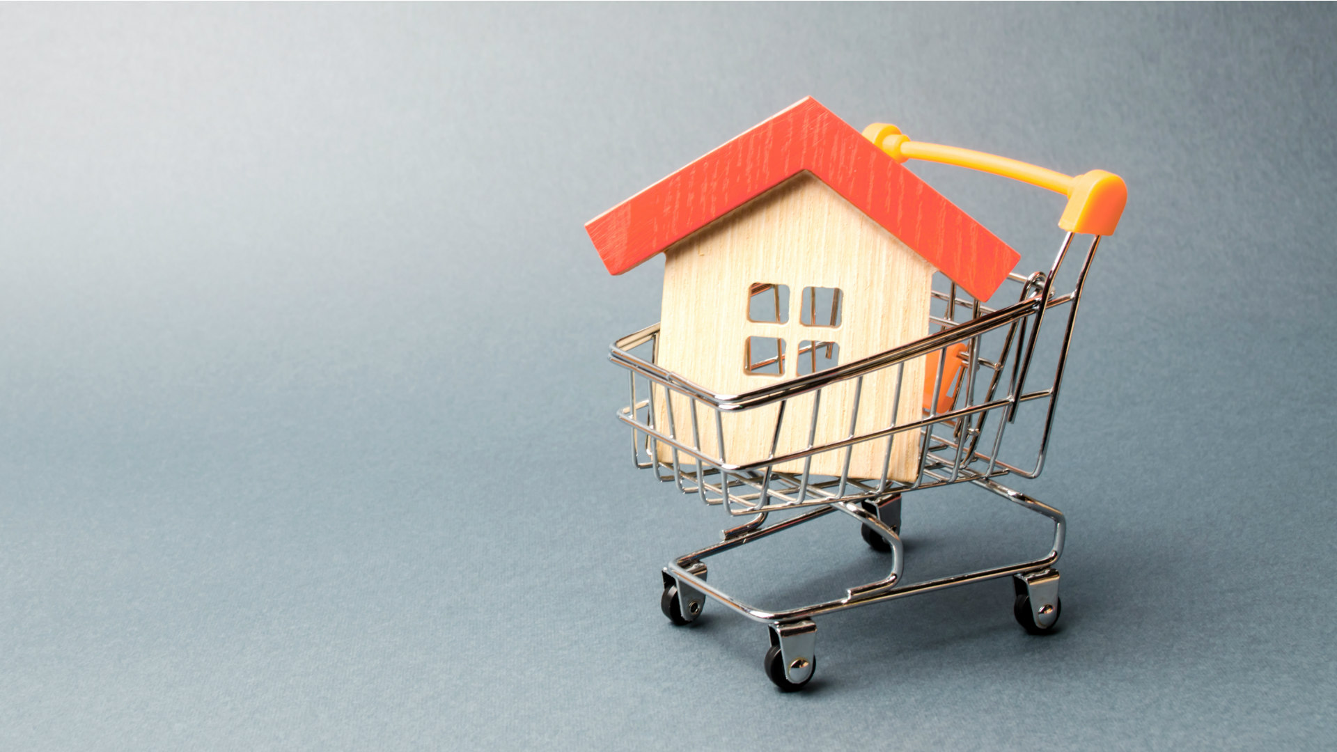 Miniatura de uma casa de madeira dentro e um carrinho de compras, representando os imóveis comprados por fundos imobiliários