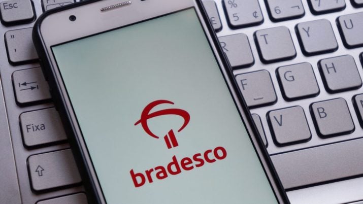 Telefone celular com tela do aplicativo do Bradesco sobre um teclado de computador Bradesco (BBDC4) dividendos