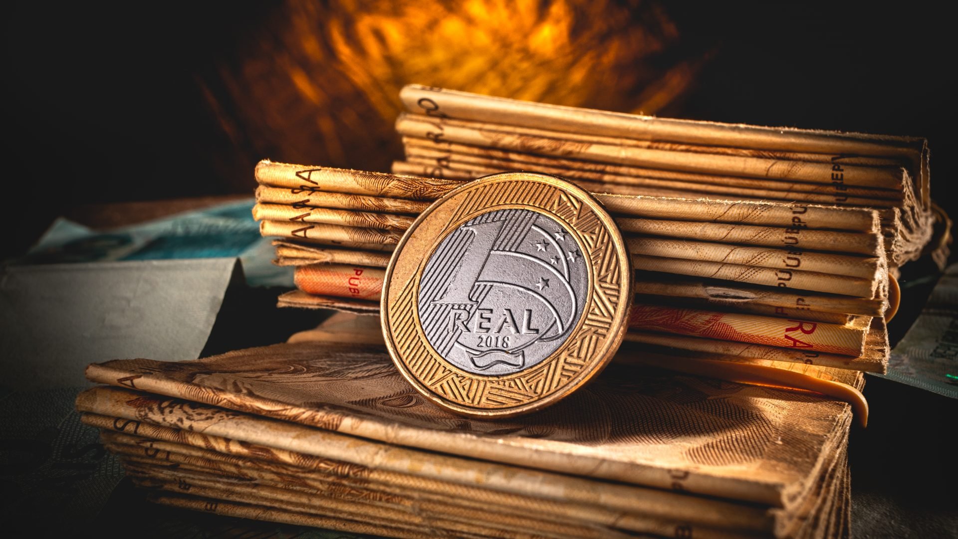 Moeda de 1 real colocada sobre uma pilha de moedas de 50 reais