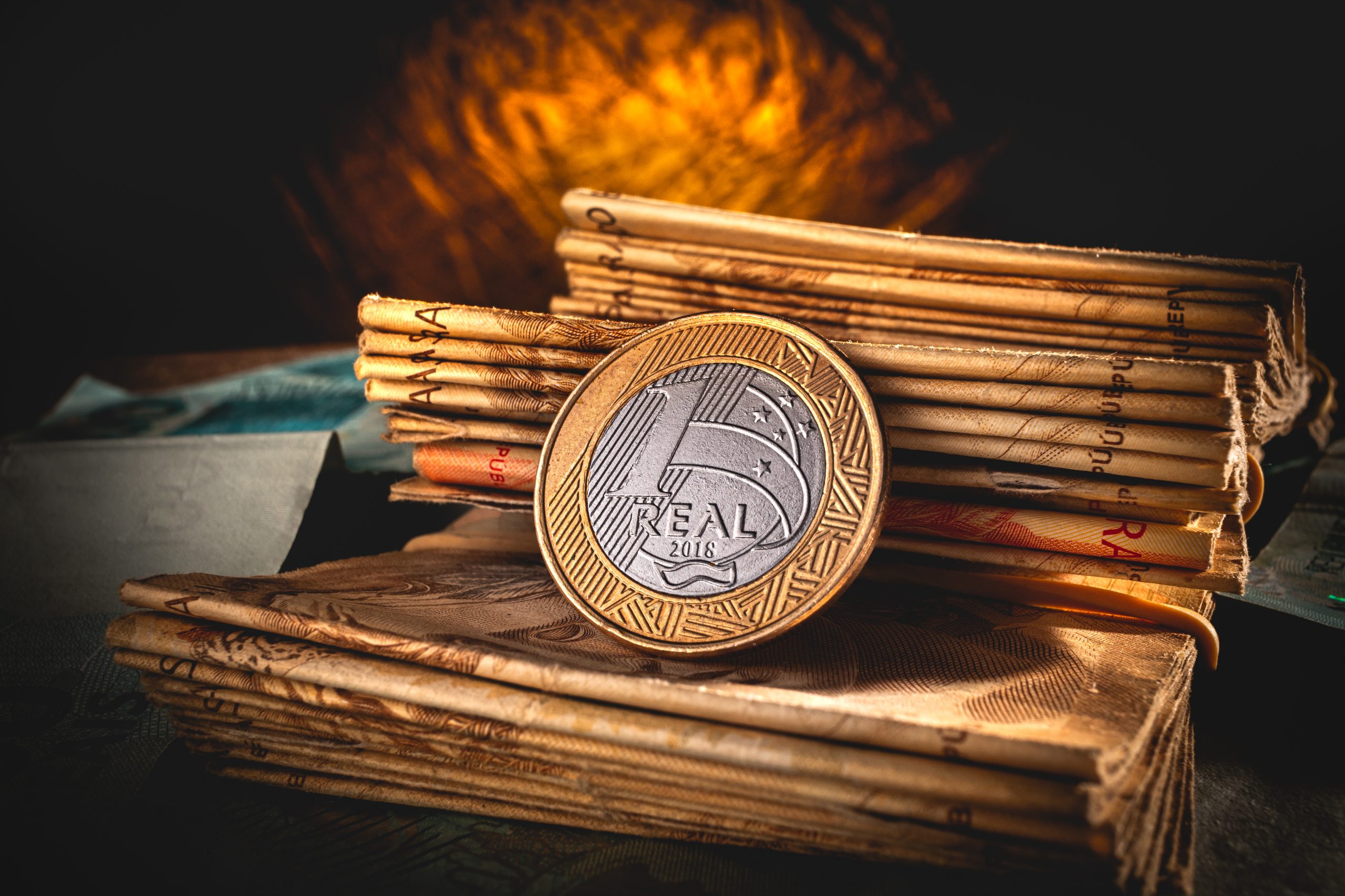 Moeda de 1 real colocada sobre uma pilha de moedas de 50 reais