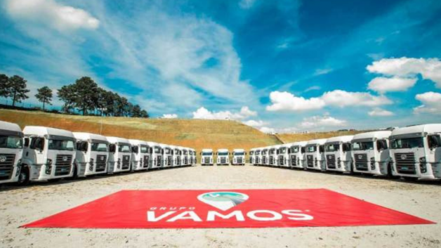 Caminhões do Grupo Vamos (VAMO3) dispostos em um estacionamento