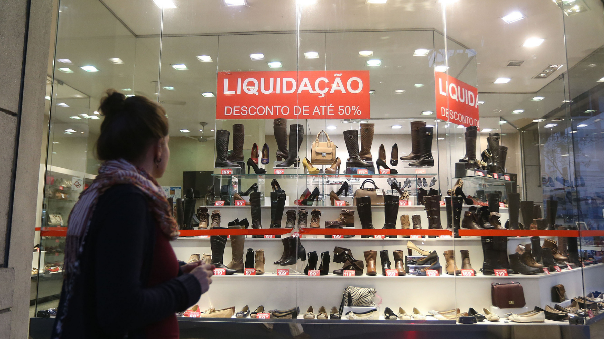 moça olha loja com a placa de liquidação