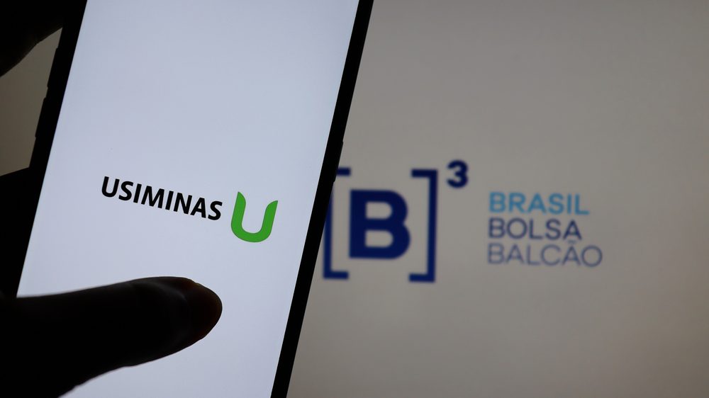 Logotipo da Usiminas em uma tela de celular com o logo da B3 ao fundo