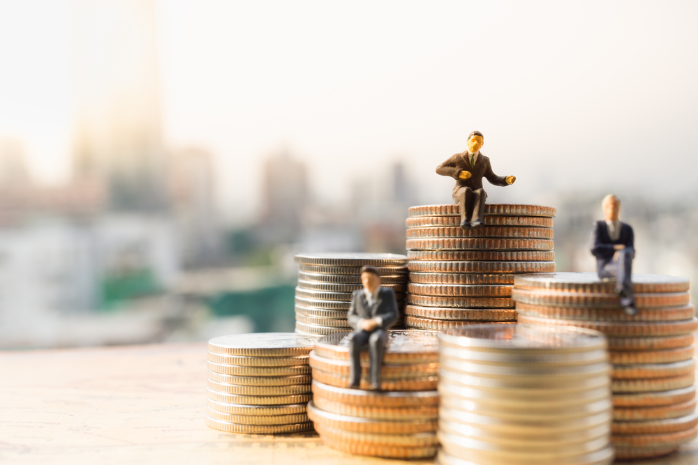 Bonecos em miniatura de homens vestidos de terno sentados em pilhas de moedas