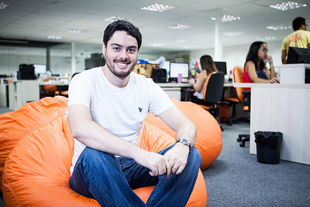 Victor Noda, CEO da Mobly, sentado em um pufe laranja no escritório
