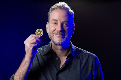 Ator da Globo Dan Stulbach segura uma moeda fictícia de Bitcoin