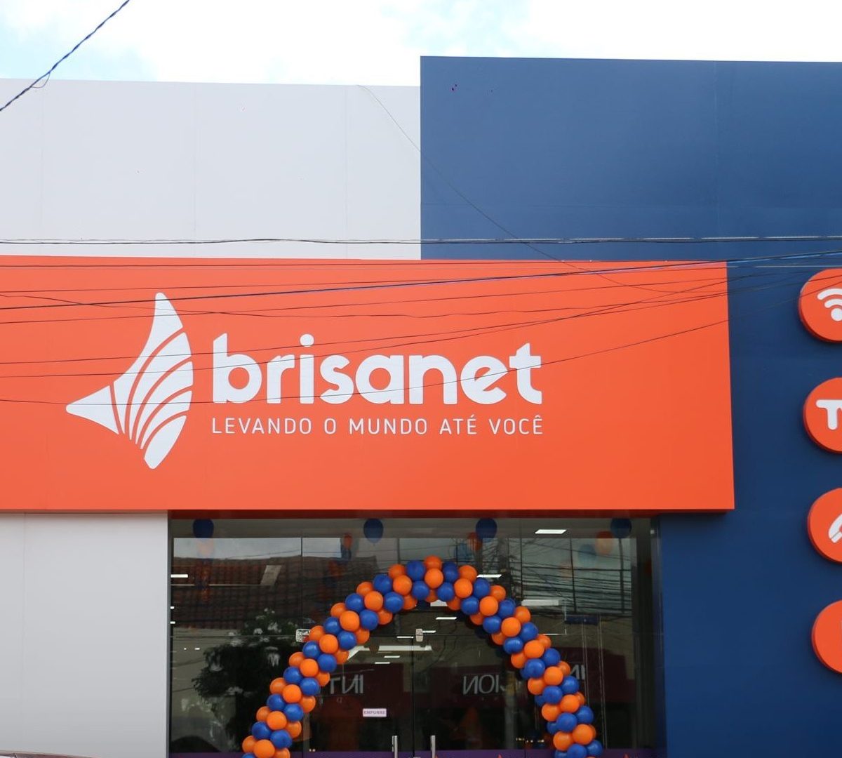 Fachada da Brisanet com arco de balões nas cores azul e laranja abaixo do logo da empresa