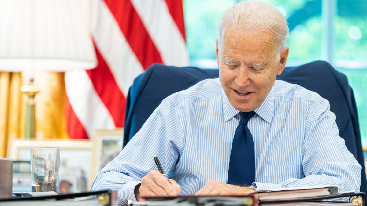 Presidente dos EUA, Joe Biden, sentado à mesa, escrevendo um memorando