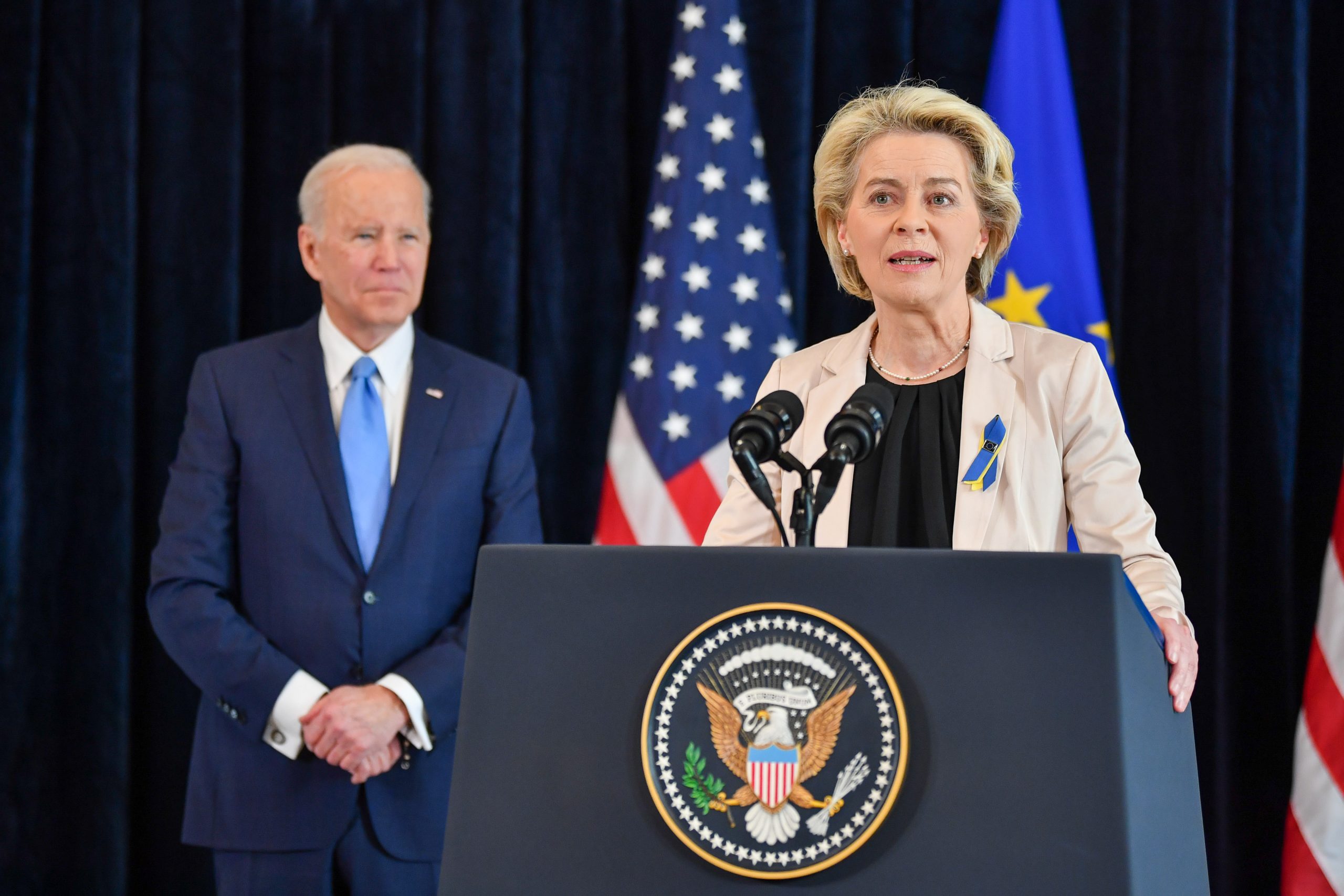 A presidente da Comissão Europeia, Ursula Von der Leyen, falando de pé em um púlpito com o presidente dos EUA, Joe Biden, de pé atrás dela
