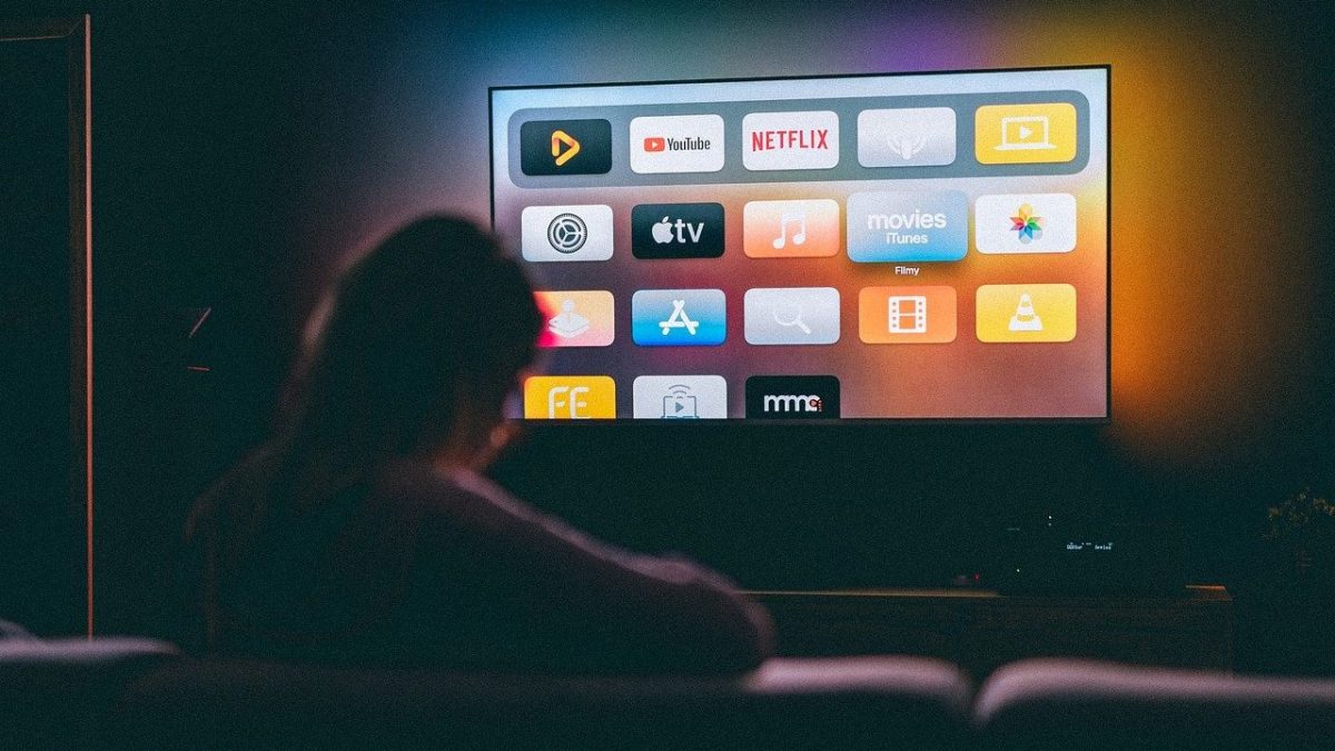Televisão smart mostrando uma pessoa assistindo