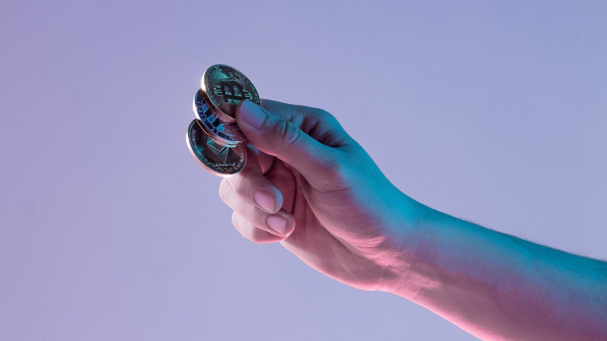 Mão entregando bitcoin para um investidor em criptomoedas; venture capitals colocam US$ 2 bilhões em cripto