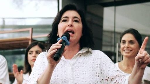 Story da senadora Simone Tebet (MDB), que veste camisa branca furadinha e está com microfone na mão