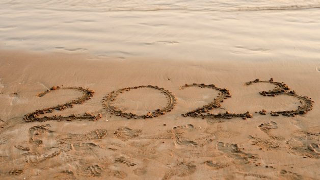O ano de 2023 escrito na areia da praia, com o mar próximo