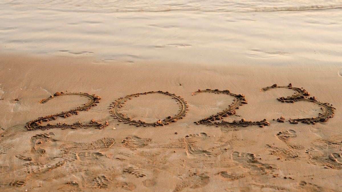 O ano de 2023 escrito na areia da praia, com o mar próximo