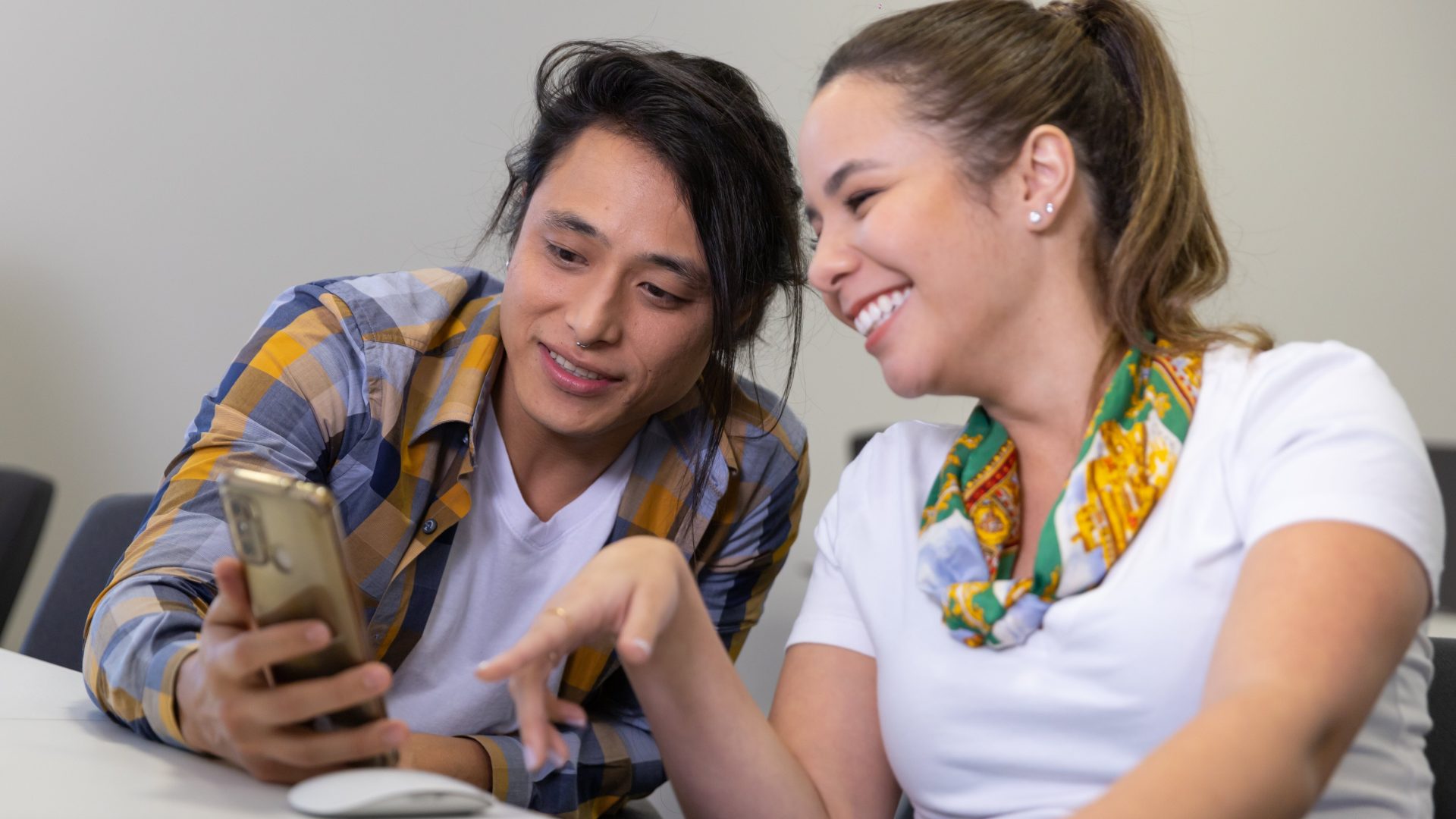 Duas pessoas observando informações em um celular; dia do estagiário; estágio