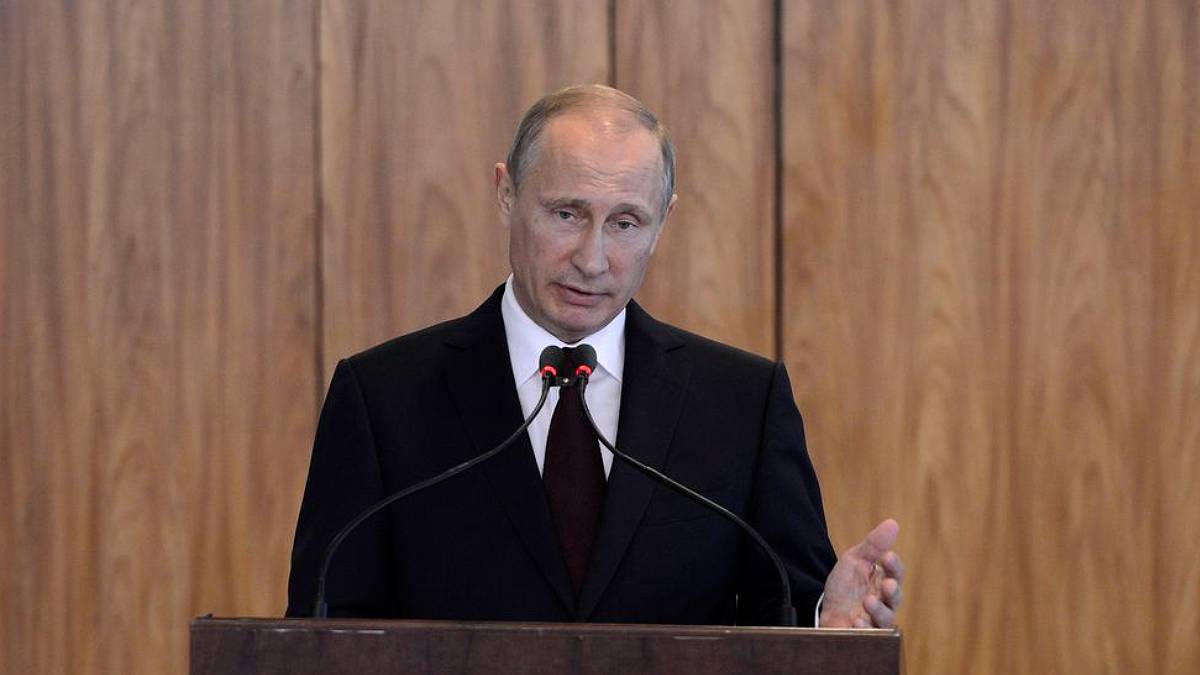 O presidente da Rússia, Vladimir Putin, de terno preto, em pé, na frente de um púlpito