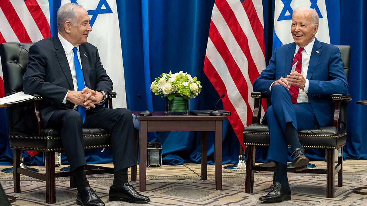 O primeiro-ministro de Isrtael, Benjamin Netanyahu, e o presidente dos EUA, Joe Biden, sentados lado a lado com as bandeiras de seus países atrás