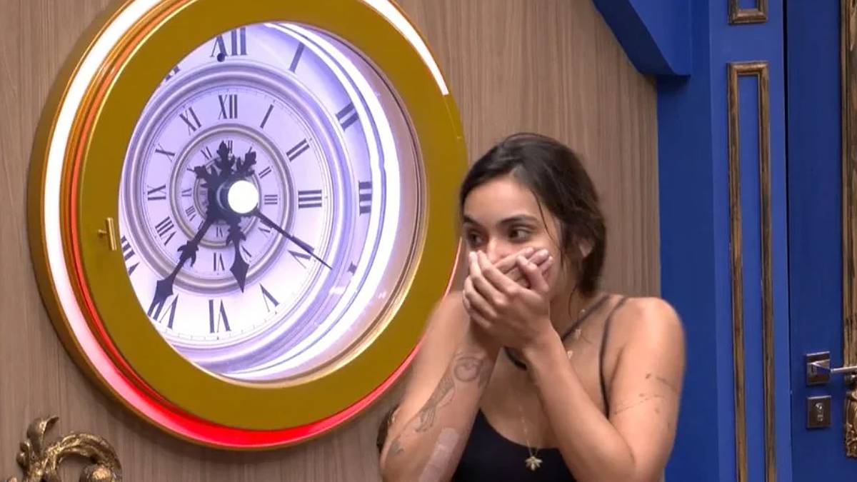 A influencer digital Vanessa Lopes está com as mãos na boca ao lado do botão de desistência do BBB 24