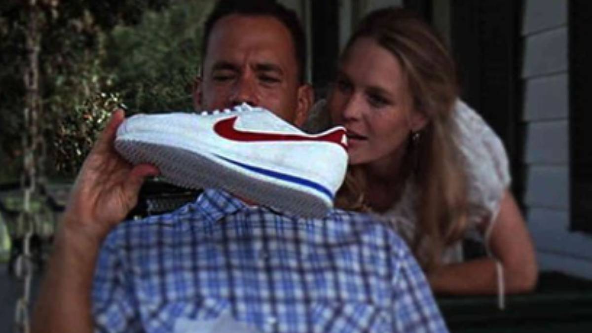 O ator Tom Hanks segura um modelo do tênis Nike Cortez nas cores branco, vermelho e azul durante o filme Forrest Gump