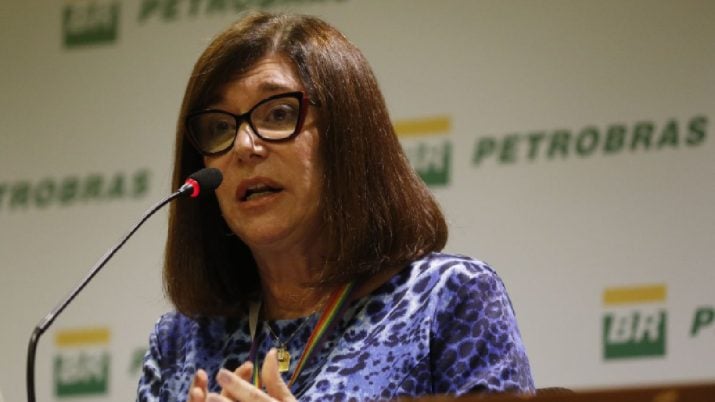 Magda Chambriard em primeiro plano com painel branco atrás, com os dizeres Petrobras