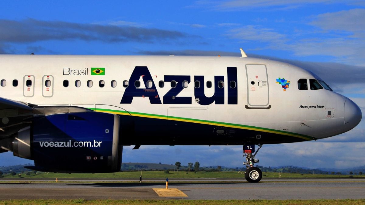 Aeronave da companhia Azul estacionado, com céu azul ao fundo. AZUL4