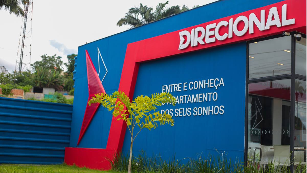 Estabelecimento da Direcional, da cor azul, com nome da empresa em cor branca e fundo vermelho, e os dizeres "entre e conheça o departamento dos seus sonhos" em cor branca.