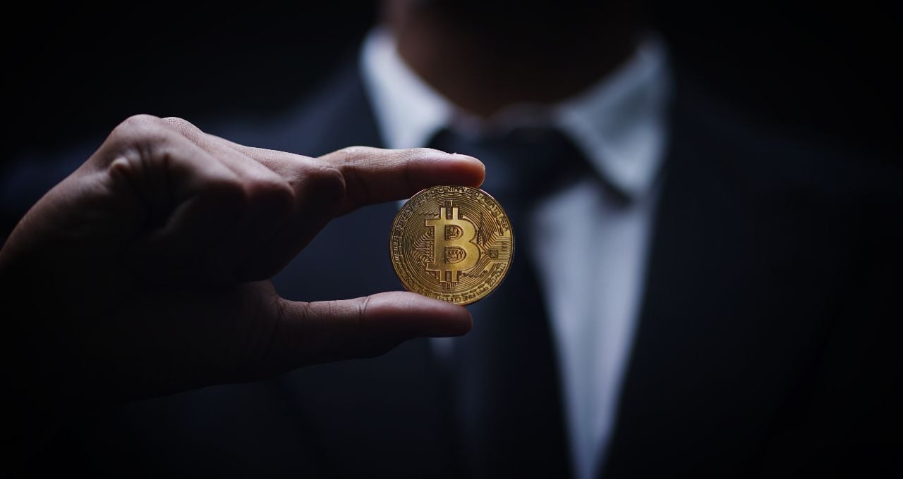 Homem segurando criptomoeda (bitcoin)