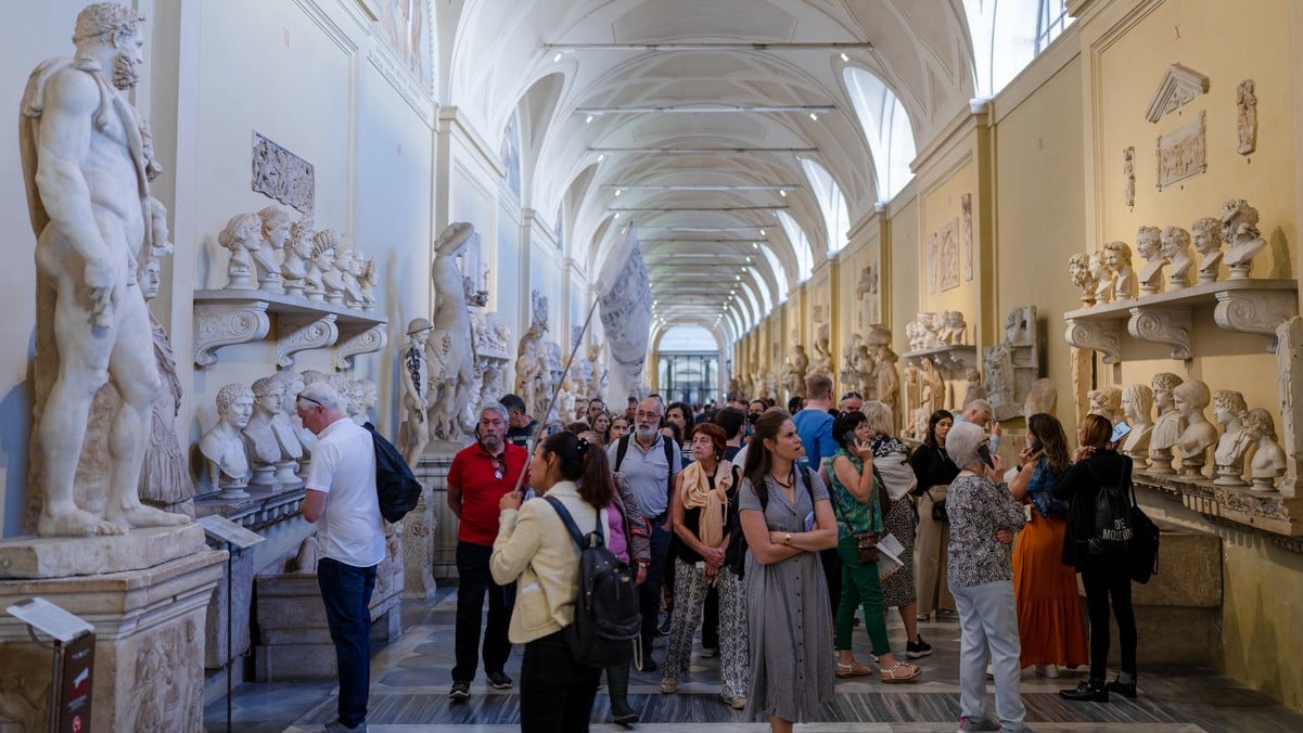 Turistas olhando para esculturas antigas de romanos no corredor do Museu Chiaramonti na Cidade do Vaticano